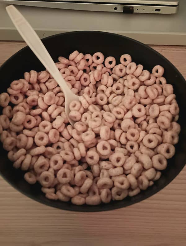 A person holding a colander filled with cereal over a sink, attempting to drain it