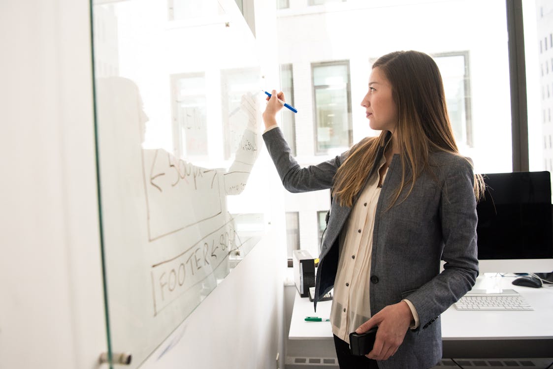 Free Woman Wearing Gray Blazer Writing on Dry-erase Board Stock Photo