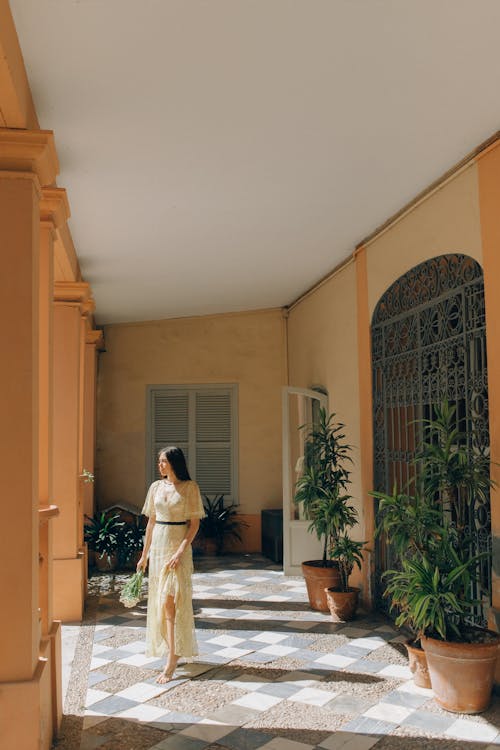 Free Woman in White Dress Standing on Brown Wooden Parquet Flooring Stock Photo